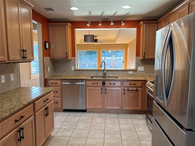 kitchen featuring light tile patterned flooring, sink, ceiling fan, light stone counters, and stainless steel appliances