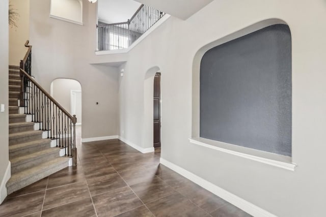 entrance foyer with dark tile patterned flooring and a towering ceiling