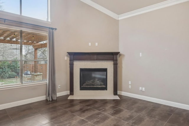 unfurnished living room featuring dark tile patterned floors, ornamental molding, and a wealth of natural light