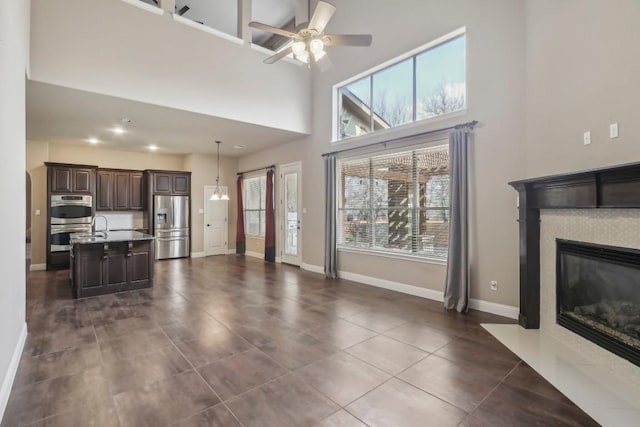 unfurnished living room with dark tile patterned flooring, a towering ceiling, and ceiling fan