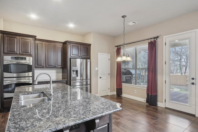 kitchen featuring pendant lighting, sink, dark brown cabinetry, and appliances with stainless steel finishes