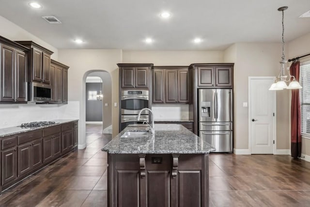 kitchen featuring dark brown cabinetry, sink, stainless steel appliances, and an island with sink