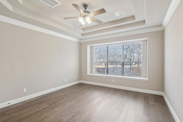 spare room with ornamental molding, dark wood-type flooring, ceiling fan, and a tray ceiling