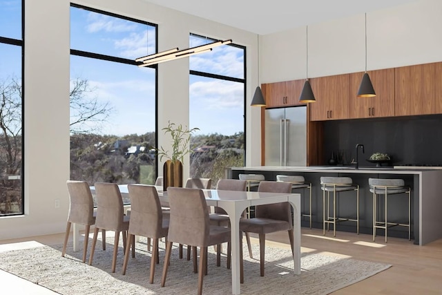 dining space with sink, a high ceiling, and light wood-type flooring