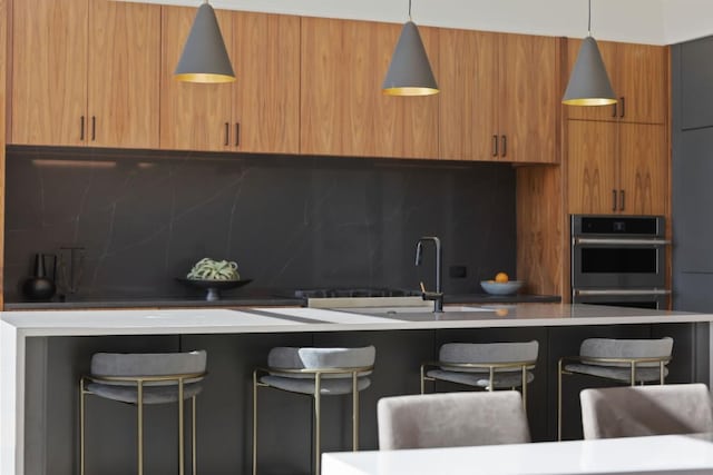 4502 Hyridge Dr, Austin, TX 78759 - kitchen featuring modern cabinets, stainless steel double oven, decorative backsplash, a breakfast bar, and light countertops