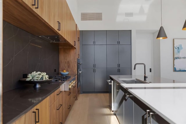 4502 Hyridge Dr, Austin, TX 78759 - kitchen with modern cabinets, backsplash, light wood finished floors, hanging light fixtures, and stainless steel appliances