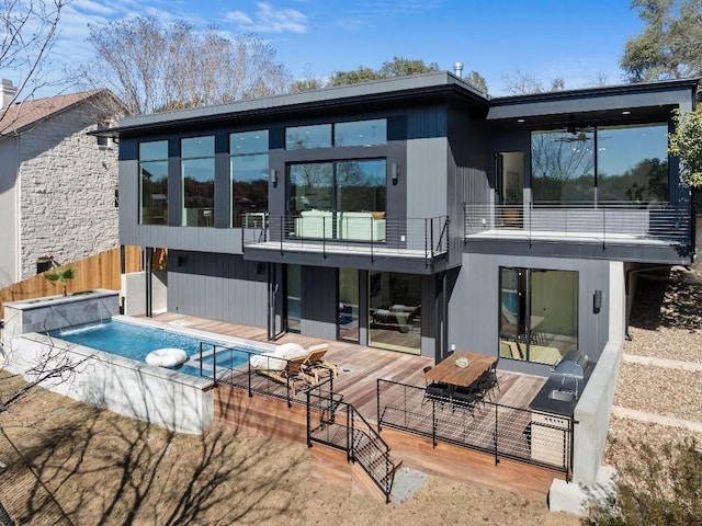 4502 Hyridge Dr, Austin, TX 78759 - back of property featuring a pool with connected hot tub, a balcony, a deck, and a ceiling fan