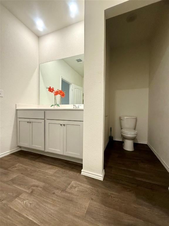 bathroom with wood-type flooring, toilet, and vanity