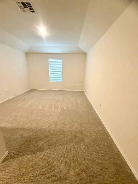 empty room with vaulted ceiling and carpet floors