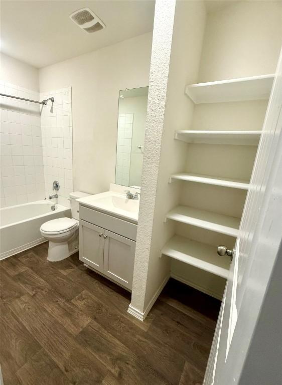 full bathroom with vanity, tiled shower / bath, wood-type flooring, and toilet