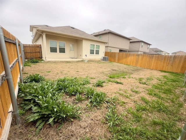 rear view of property featuring cooling unit and a lawn