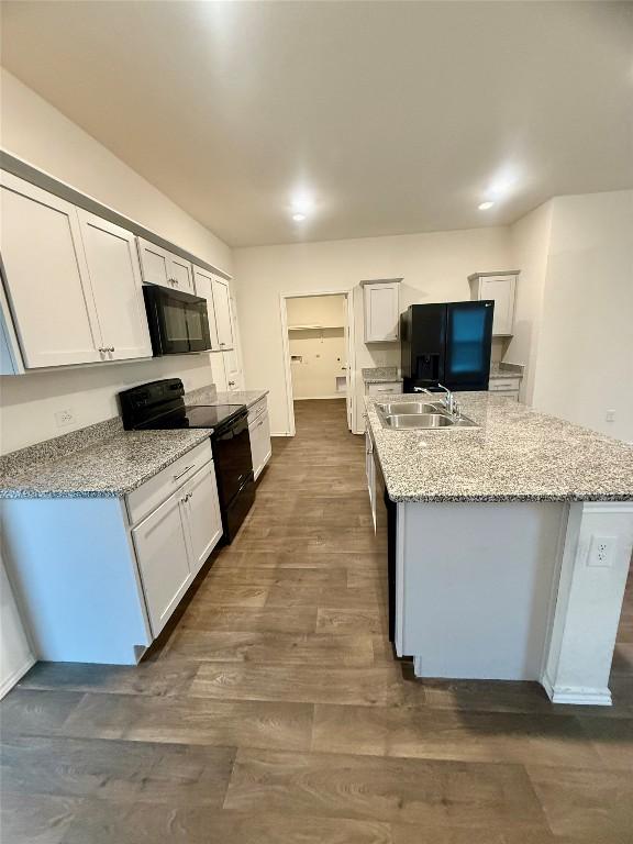 kitchen featuring sink, a center island with sink, white cabinets, and black appliances