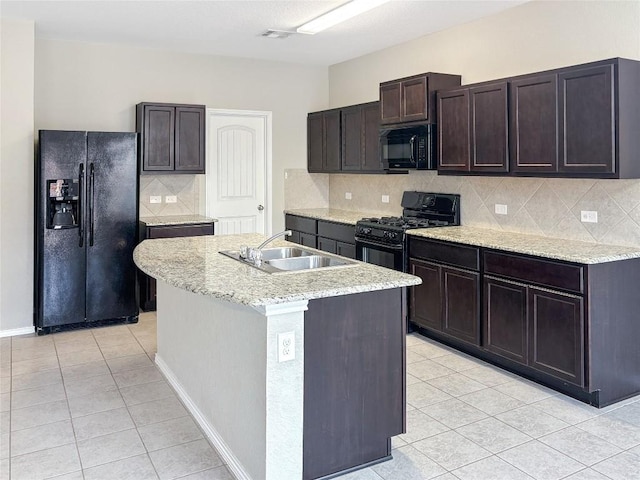 kitchen with dark brown cabinetry, an island with sink, sink, and black appliances