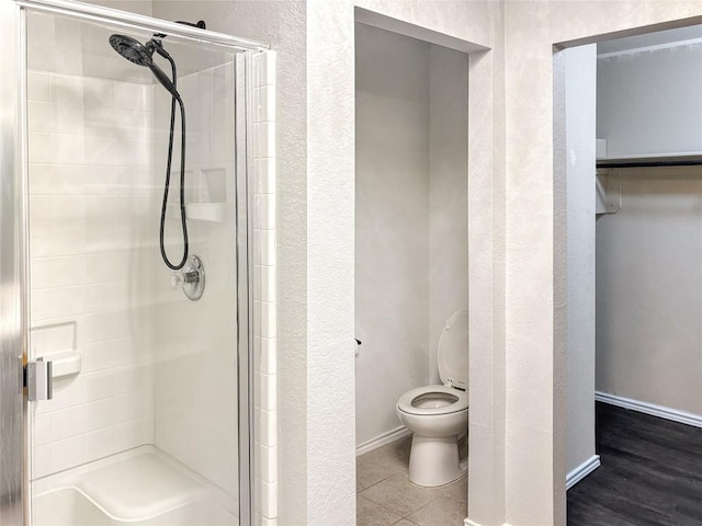 bathroom with tile patterned flooring, a shower with door, and toilet