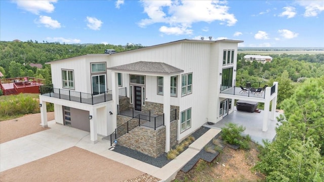 117 Nakalele Ln, Bastrop, TX 78602 - modern home featuring a balcony, an attached garage, stone siding, and concrete driveway