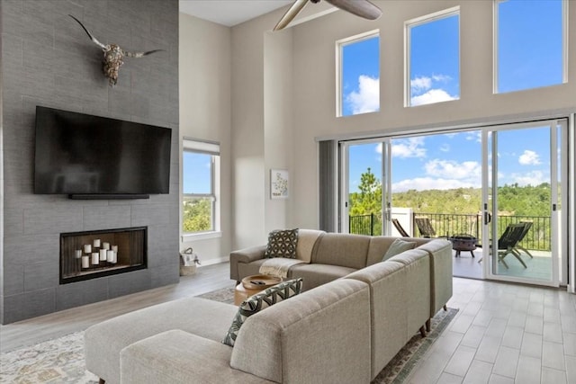 117 Nakalele Ln, Bastrop, TX 78602 - living room with a large fireplace, a high ceiling, ceiling fan, wood finished floors, and baseboards