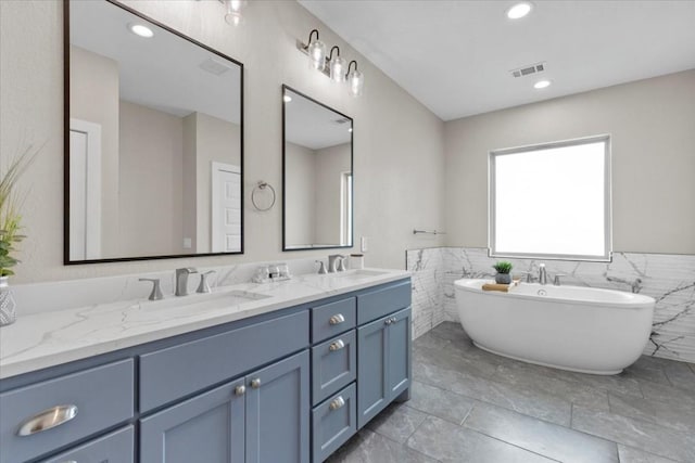 bathroom with vanity, a tub, and tile walls