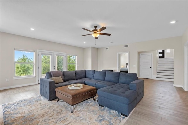 living room with french doors, ceiling fan, and light wood-type flooring