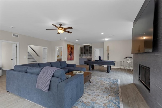 117 Nakalele Ln, Bastrop, TX 78602 - living room featuring a glass covered fireplace, light wood finished floors, billiards, a ceiling fan, and stairway