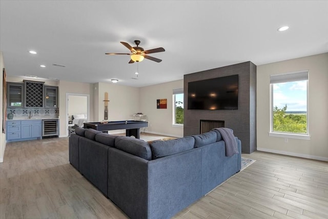 living room featuring light hardwood / wood-style flooring, indoor wet bar, wine cooler, a fireplace, and pool table