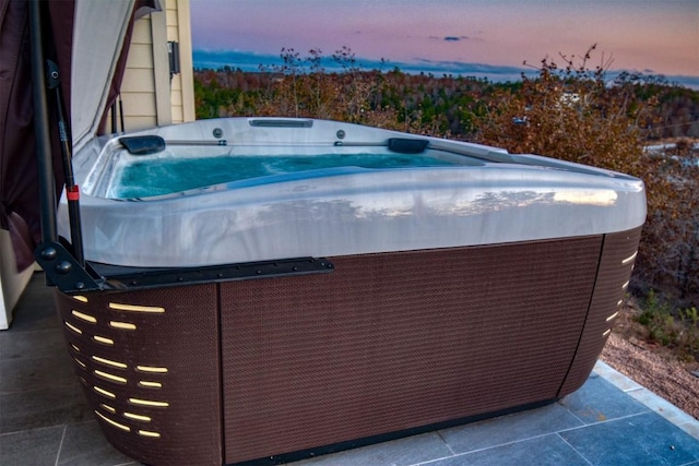 pool at dusk with a hot tub