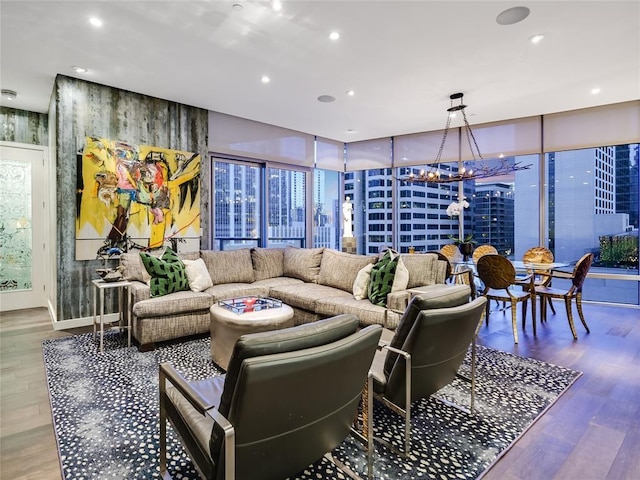 living room with hardwood / wood-style flooring, a wall of windows, and an inviting chandelier