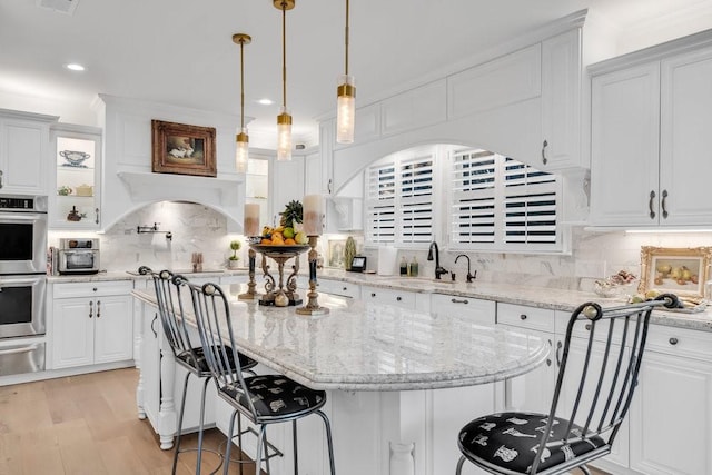 1027 Challenger, Lakeway, TX 78734 - kitchen with a sink, double oven, white cabinetry, a kitchen island, and recessed lighting