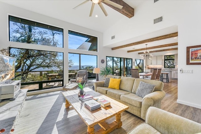 living room featuring beamed ceiling, light hardwood / wood-style flooring, and a high ceiling