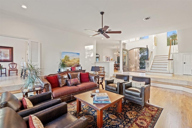 living room with ceiling fan with notable chandelier and light hardwood / wood-style floors