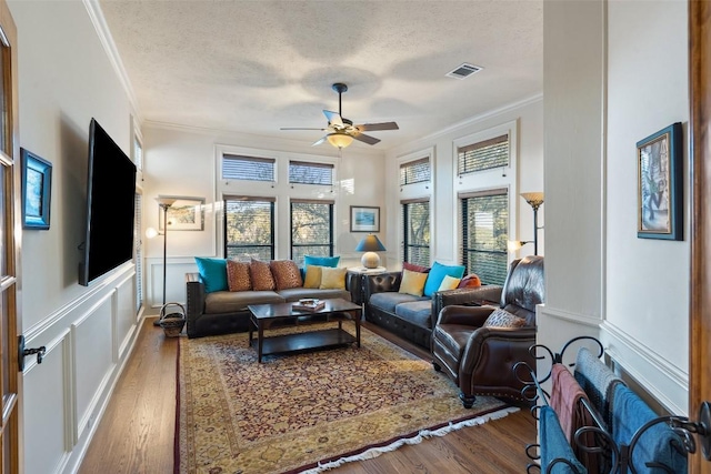 living room with hardwood / wood-style flooring, ceiling fan, ornamental molding, and a textured ceiling