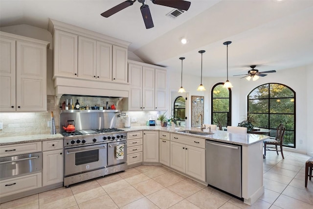 kitchen featuring sink, appliances with stainless steel finishes, light stone countertops, vaulted ceiling, and kitchen peninsula