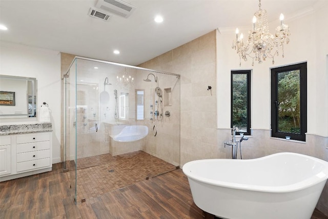 bathroom with shower with separate bathtub, a chandelier, tile walls, vanity, and hardwood / wood-style flooring