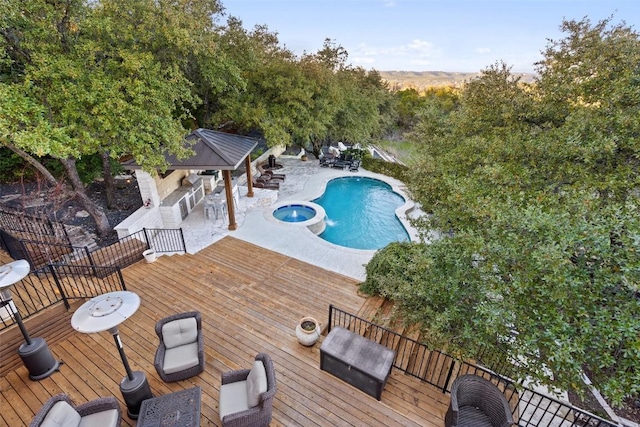 view of pool featuring an in ground hot tub, exterior bar, a gazebo, and a deck