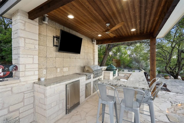 view of patio / terrace with a bar, grilling area, ceiling fan, and an outdoor kitchen