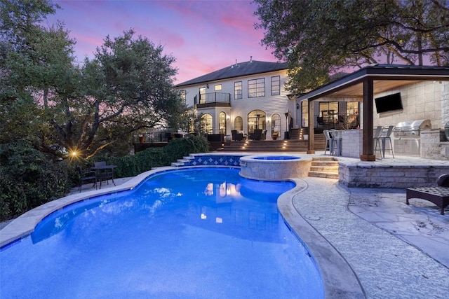 view of pool with area for grilling, exterior bar, a patio, and an in ground hot tub