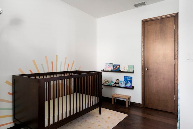 bedroom with a crib and dark hardwood / wood-style flooring