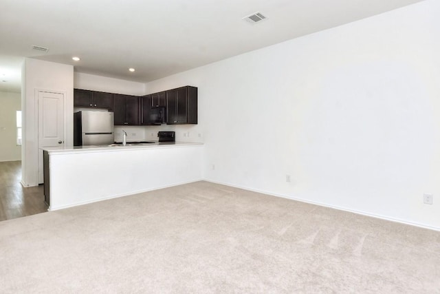 605 Rancho Del Cielo Loop, Jarrell, TX 76537 - kitchen with freestanding refrigerator, black microwave, light colored carpet, recessed lighting, and baseboards