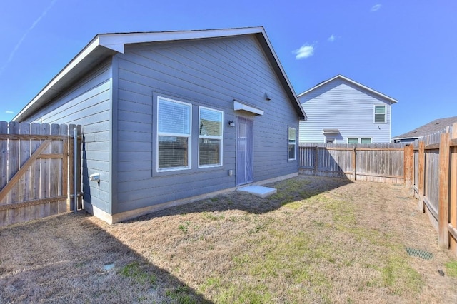 back of house featuring a fenced backyard and a yard