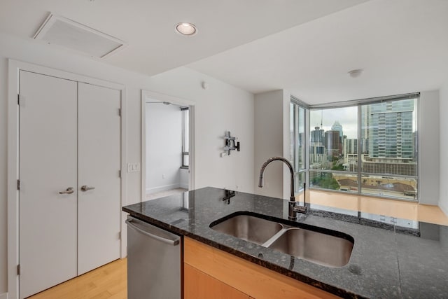 kitchen featuring light hardwood / wood-style floors, sink, stainless steel dishwasher, and dark stone counters