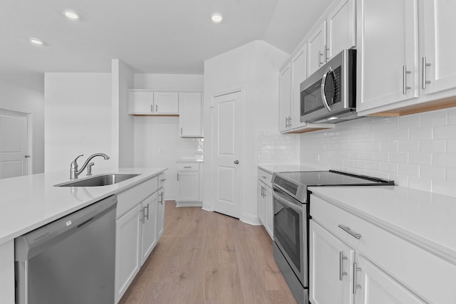 kitchen with white cabinetry, stainless steel appliances, sink, and light wood-type flooring