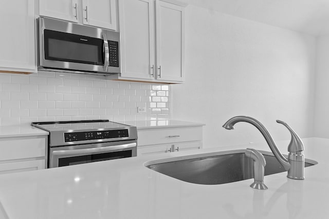 kitchen with stainless steel appliances, white cabinetry, sink, and decorative backsplash