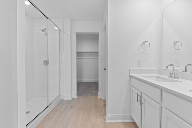 bathroom featuring wood-type flooring, a shower with shower door, and vanity