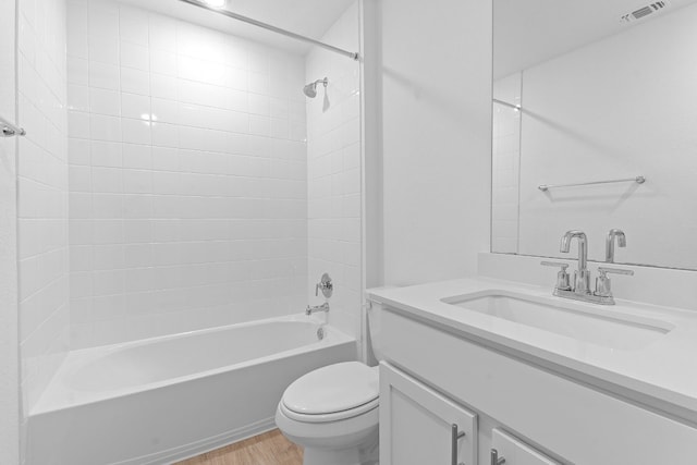 full bathroom with hardwood / wood-style floors, vanity, toilet, and tiled shower / bath