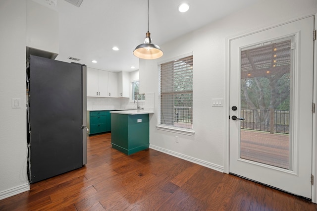 kitchen featuring dark wood finished floors, light countertops, white cabinets, freestanding refrigerator, and a peninsula
