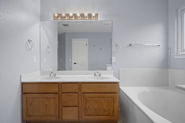 bathroom featuring visible vents, a sink, a bath, and double vanity