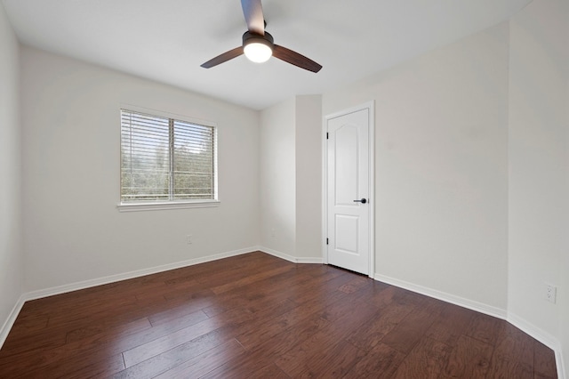 spare room featuring baseboards, a ceiling fan, and dark wood finished floors