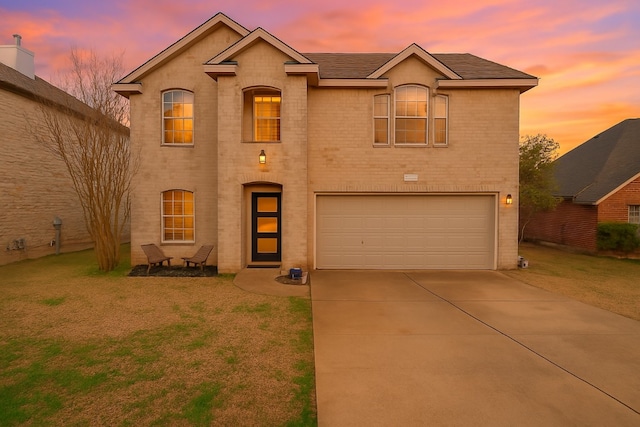traditional-style house with an attached garage, a yard, driveway, and brick siding
