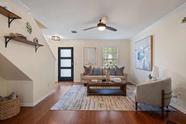living area featuring a ceiling fan, baseboards, wood finished floors, visible vents, and ornamental molding