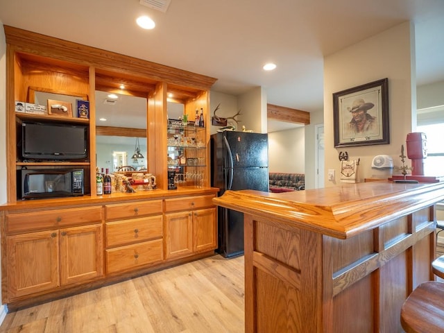 bar with light hardwood / wood-style floors, wood counters, and black appliances