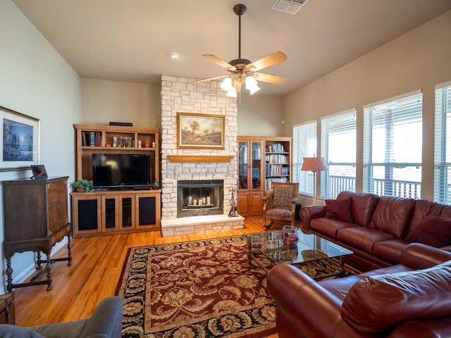 living room featuring a fireplace, ceiling fan, and light wood-type flooring
